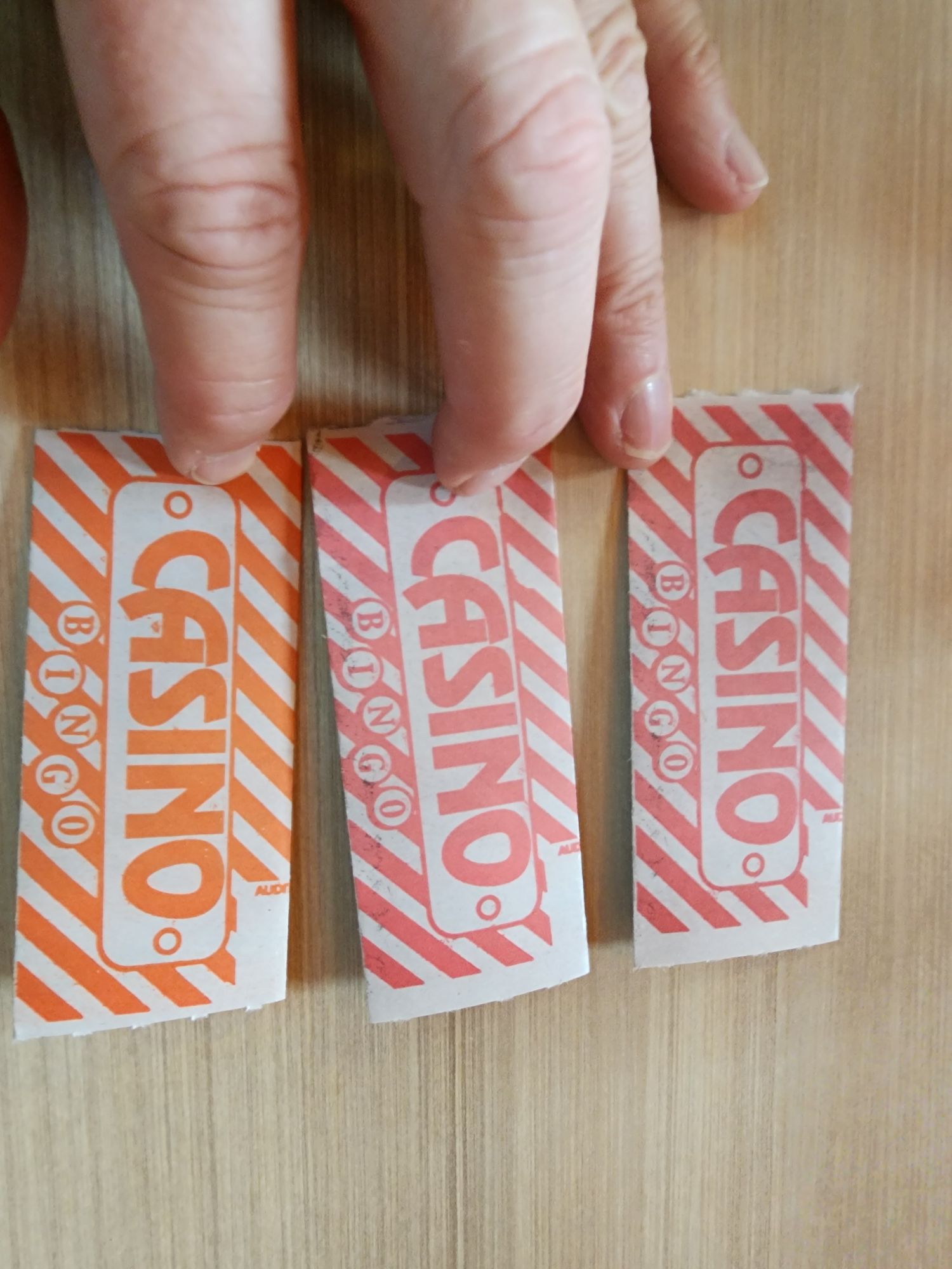 a hand holding three folded bingo cards with the word "CASINO" on them.